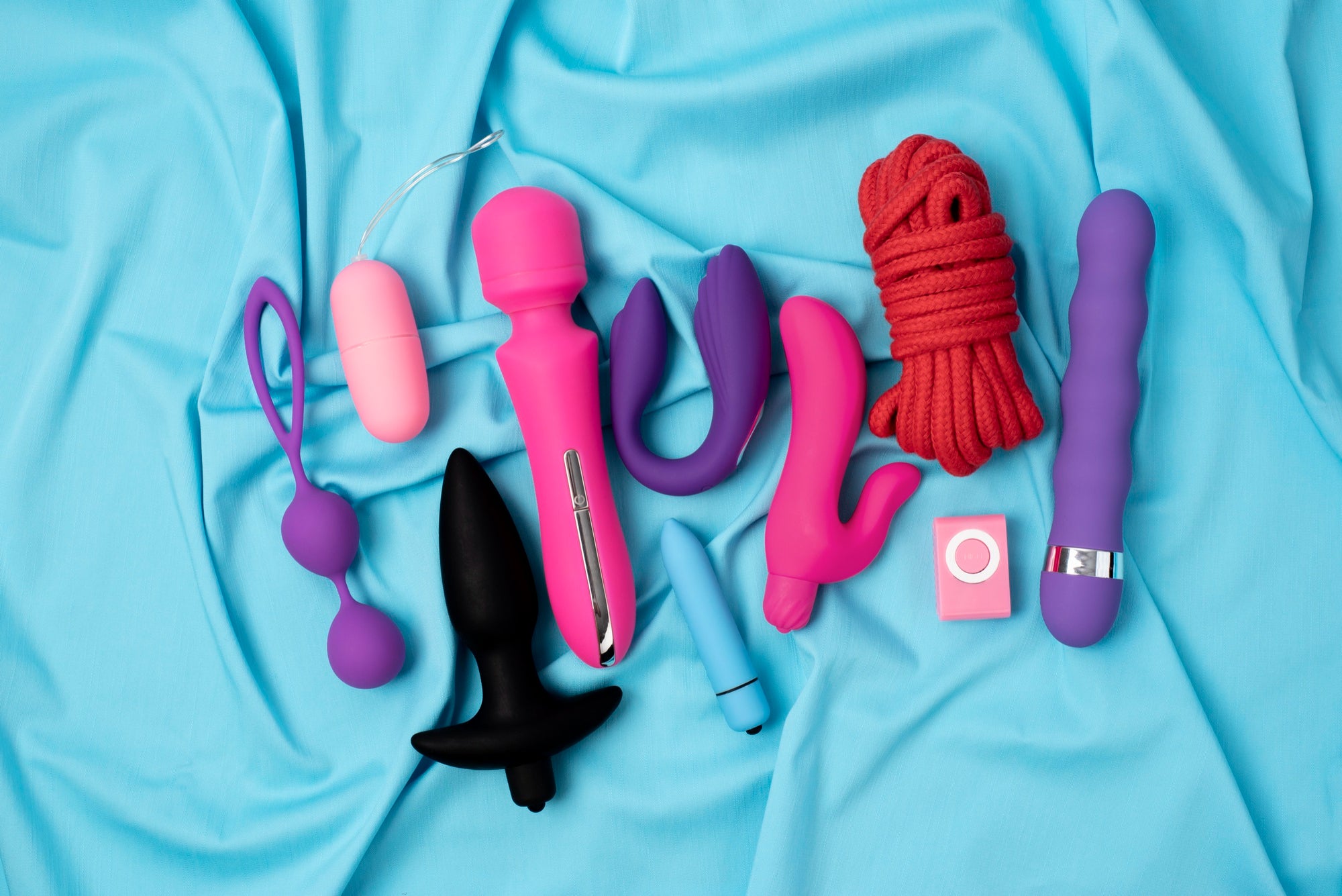 Gros plan sur des jouets sexuels variés pour adultes posés sur fond blu