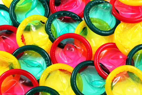 Gros plan de préservatifs colorés déroulés en rouge, jaune et vert.