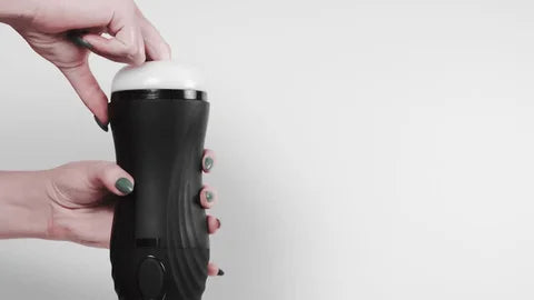 Black handheld male masturbator with a flexible silicone opening, on a white background.