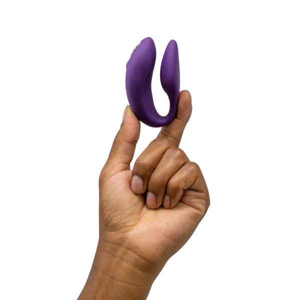 Vibrateur de couple en silicone violet en forme de U tenu entre les doigts.