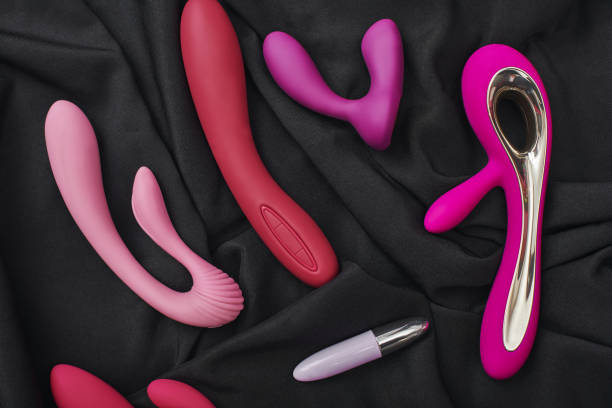 Collection de sextoys modernes en silicone coloré, présentés sur un tissu noir, utilisés pour les jeux érotiques.