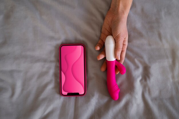 Vibrateur contrôlé à distance avec application mobile sur un lit gris.
